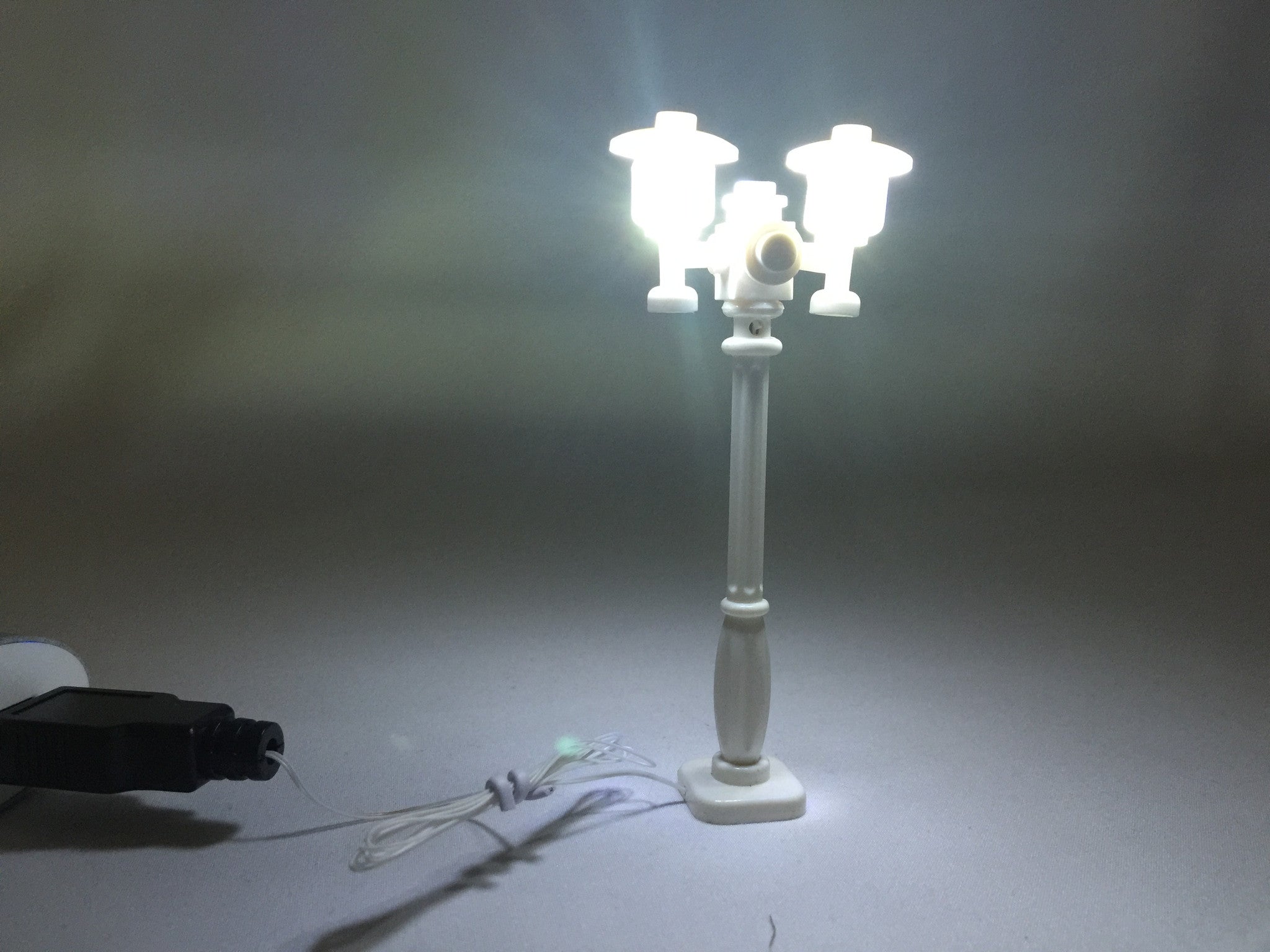 Brick Loot LED Lighting for LEGO - White Double Light Street Lamp for LEGO Cities, with a white wire, powered through USB. In this photo, the lights are on.